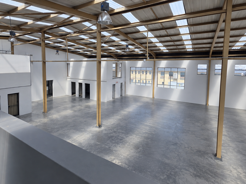 Spacious industrial warehouse featuring a high-clearance steel portal frame, polished concrete flooring, and abundant natural light through translucent roof panels.