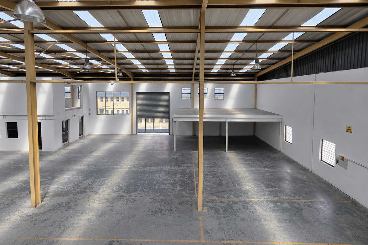 Spacious industrial warehouse featuring a high-clearance steel portal frame, mezzanine level, roller shutter door, and abundant natural light through integrated roof skylights.