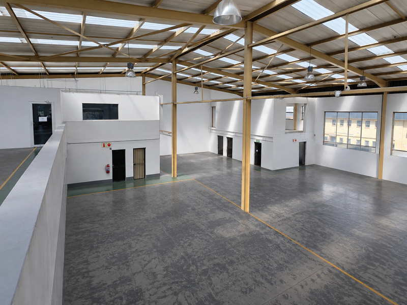 Spacious industrial warehouse featuring a high-clearance steel portal frame, translucent roof panels for natural light, epoxy flooring, and a mezzanine level.