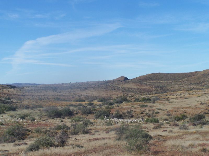 A scenic view of the expansive, arid landscape featuring rolling hills and natural vegetation typical of the surrounding farm environment.