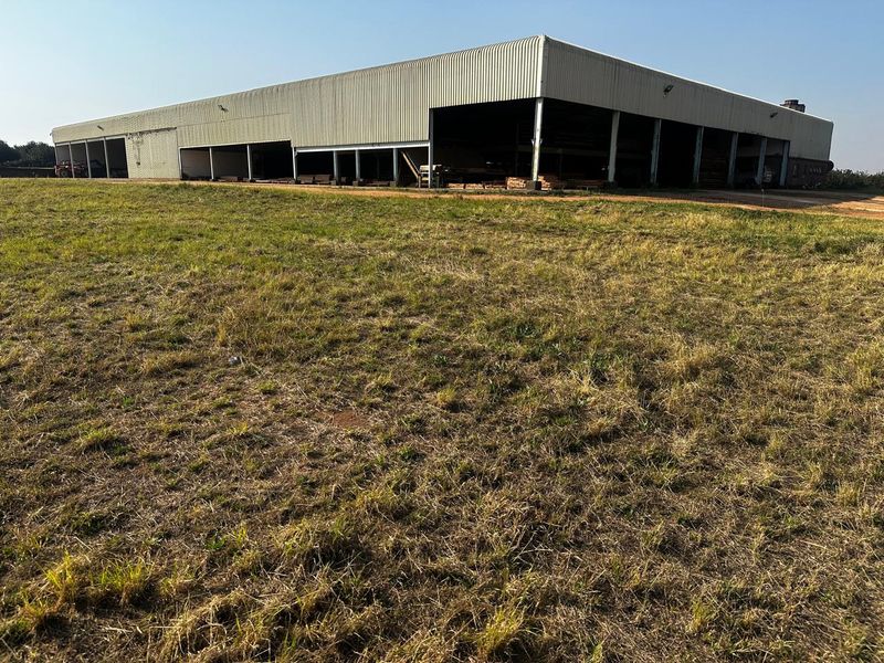 Large industrial-style open-bay storage shed or utility building situated on a rural farm property.