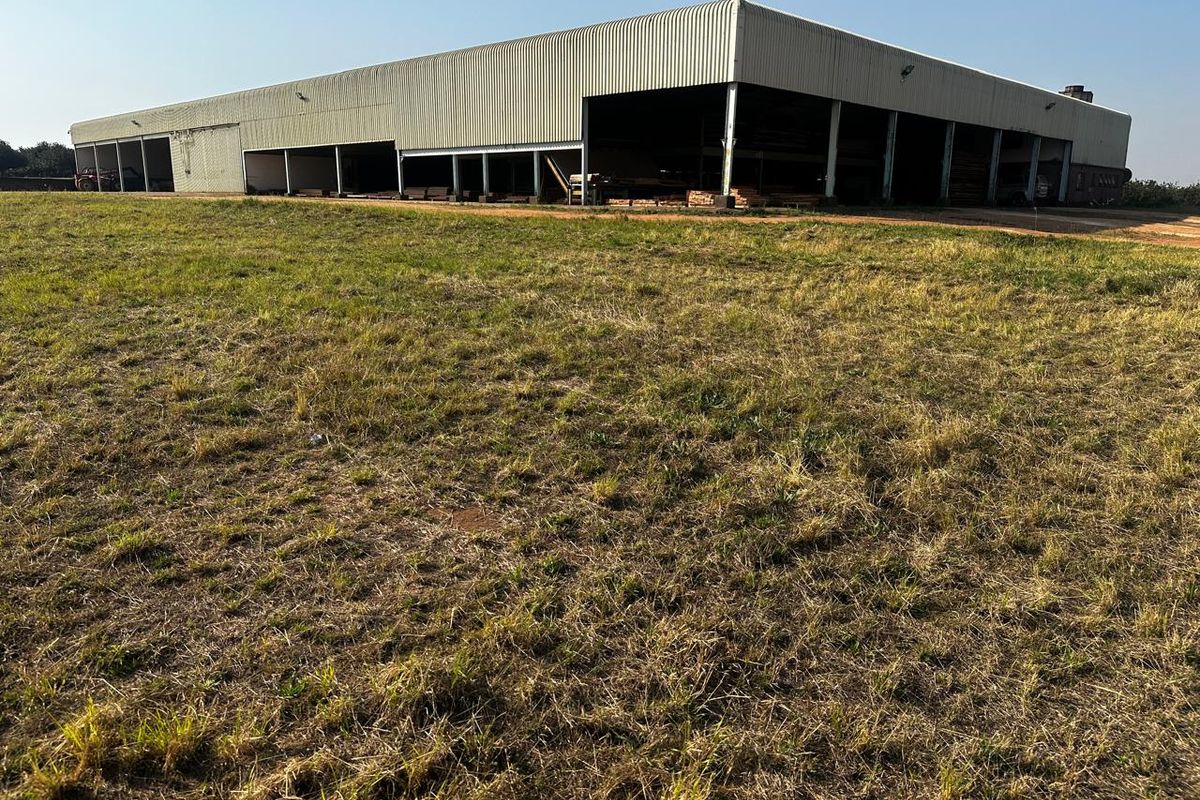 Large industrial-style open-bay storage shed or utility building situated on a rural farm property.