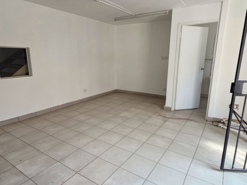 An empty, functional utility space featuring tiled flooring, a security gate, and an internal window, suitable for various industrial or storage purposes.