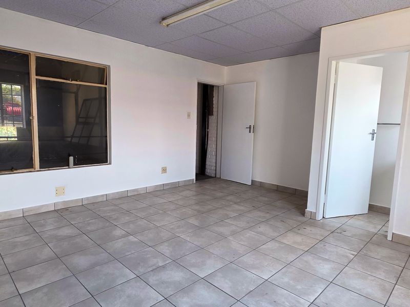 An empty, functional office space featuring tiled flooring, a suspended ceiling, and neutral walls, suitable for a variety of commercial or industrial business uses.