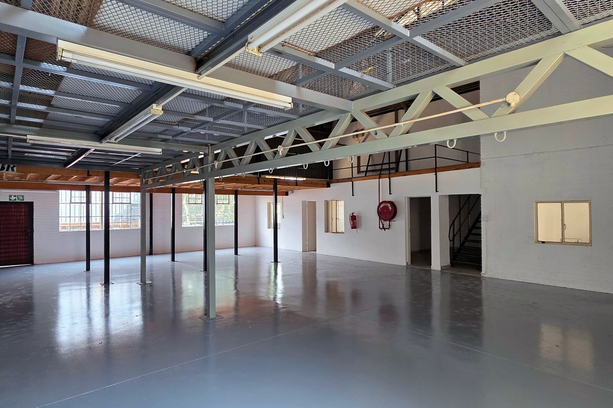 Spacious industrial open-plan warehouse area featuring a mezzanine level, durable epoxy flooring, steel structural trusses, and secure access points.
