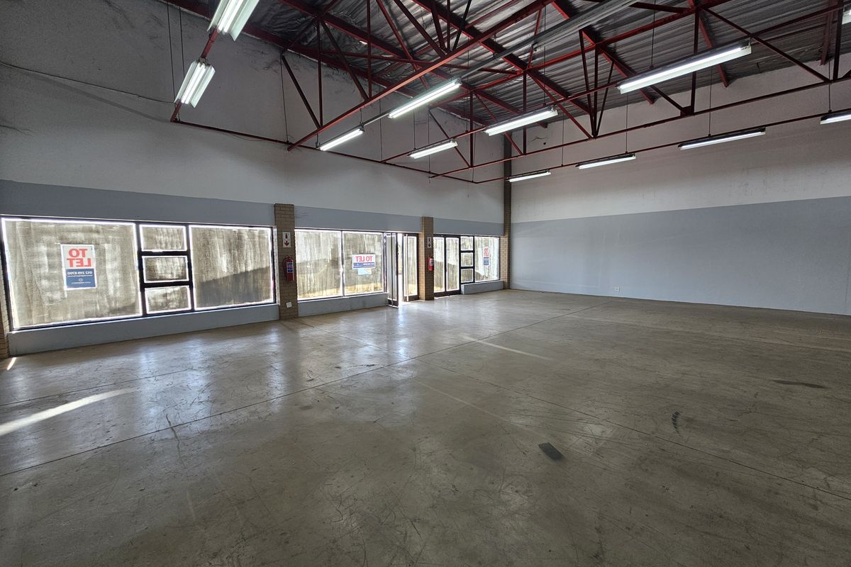 Spacious open-plan retail unit featuring high exposed steel roof trusses, polished concrete flooring, and large street-facing display windows for maximum visibility.