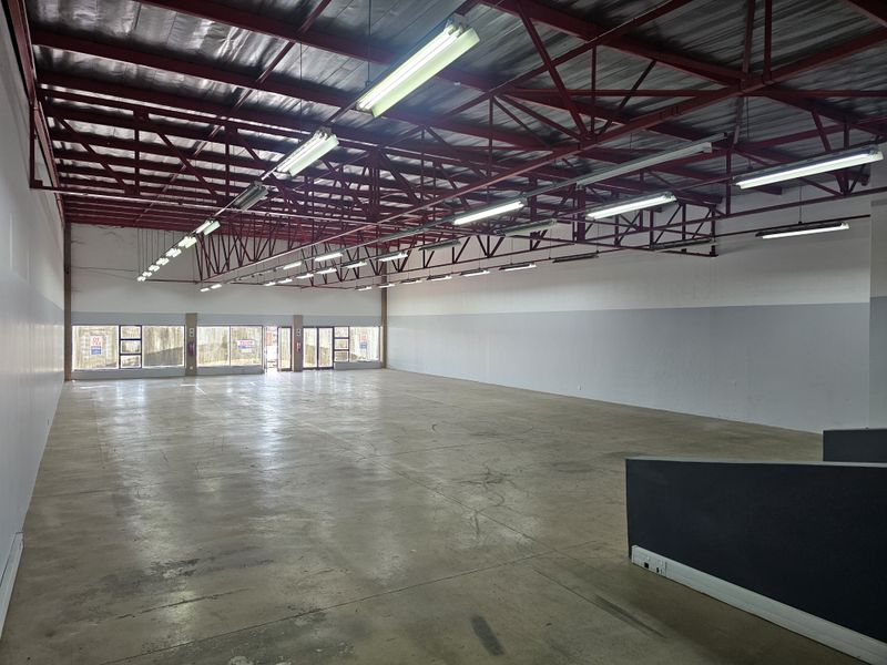 Spacious open-plan retail unit featuring high exposed steel roof trusses, polished concrete flooring, and large glass frontage providing excellent natural light and visibility.