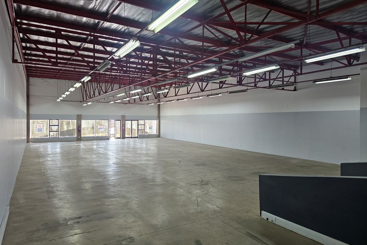 Spacious open-plan retail unit featuring high exposed steel roof trusses, polished concrete flooring, and large glass frontage providing excellent natural light and visibility.