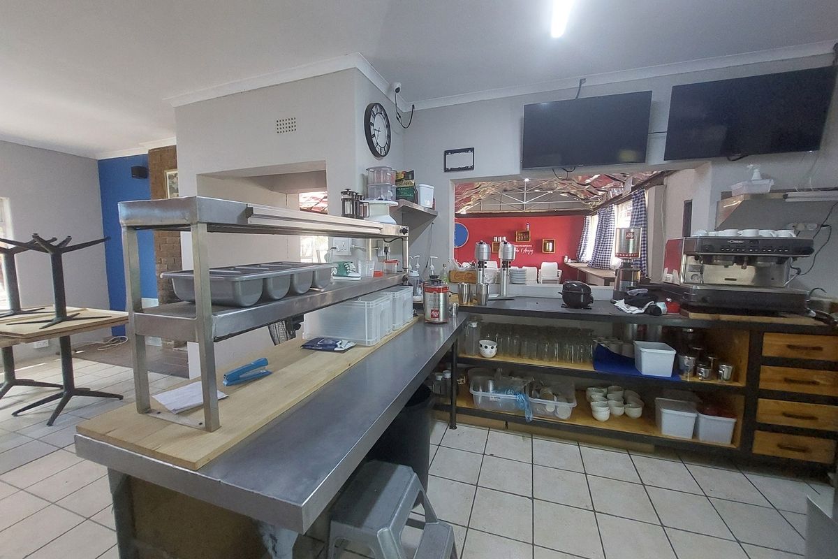 A functional commercial kitchen area featuring stainless steel prep counters, tiled flooring, and built-in shelving, suitable for restaurant operations.