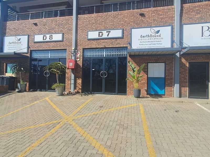Front elevation of an industrial unit complex featuring brick facade, glass entrance doors, and designated paved parking bays.