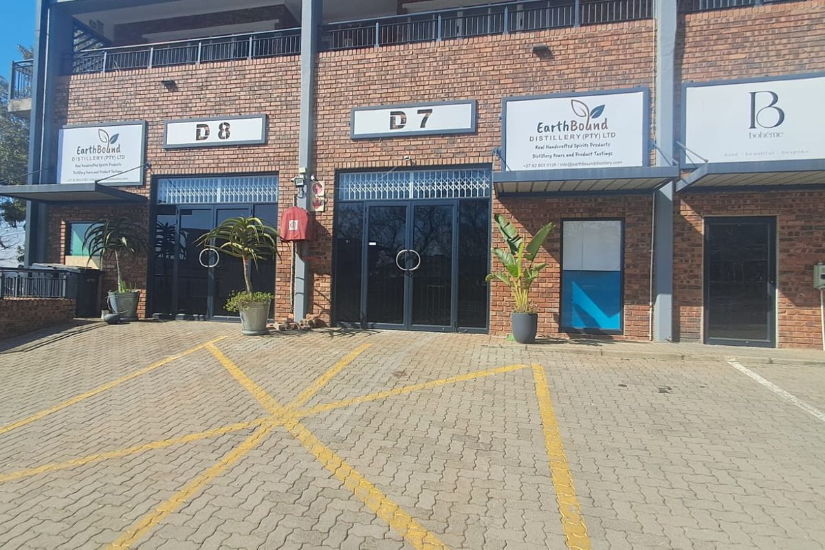 Front elevation of an industrial unit complex featuring brick facade, glass entrance doors, and designated paved parking bays.