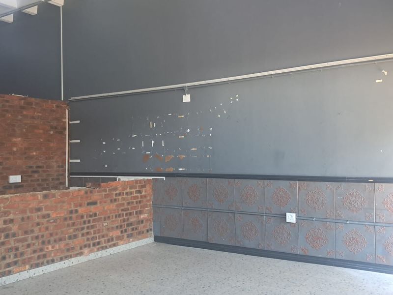 An industrial utility space featuring exposed brickwork, decorative wall paneling, and durable terrazzo flooring, currently vacant and ready for refurbishment.