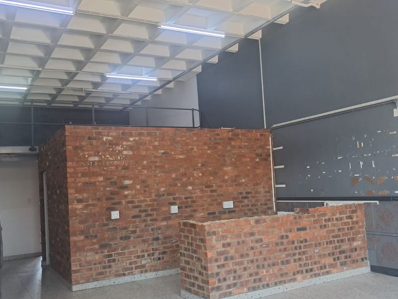 Industrial utility space featuring an exposed waffle slab ceiling, mezzanine level with metal staircase, and exposed brick partitions suitable for commercial or workshop use.