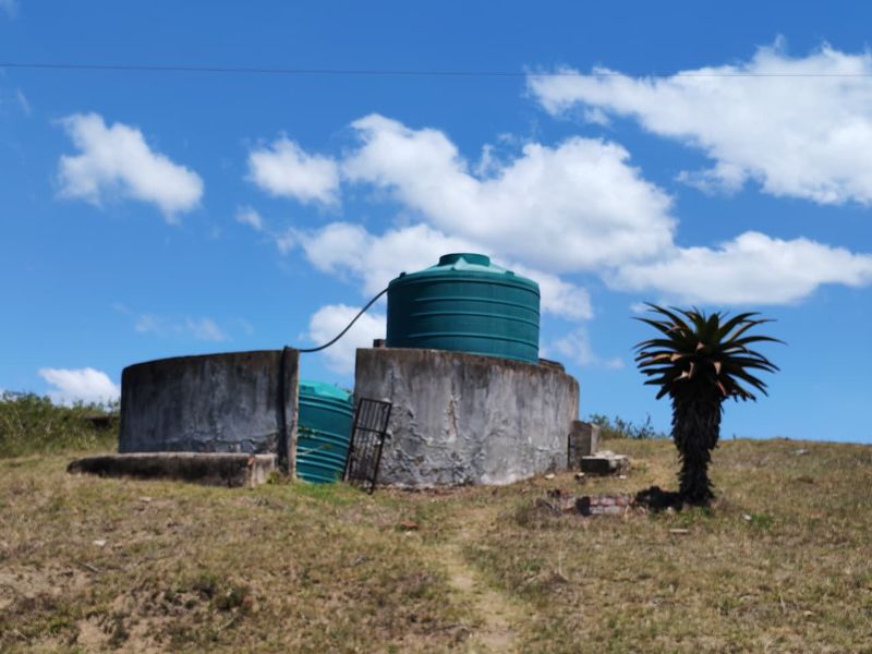 Outdoor utility area featuring large green water storage tanks set within a weathered concrete retaining structure on the farm property.