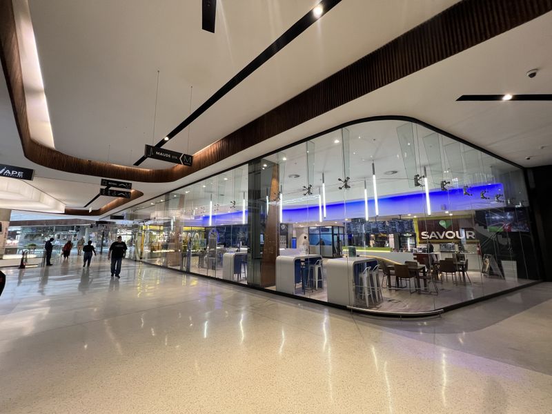 Modern retail storefront with expansive glass frontage, polished flooring, and integrated lighting, located within a contemporary shopping center environment.