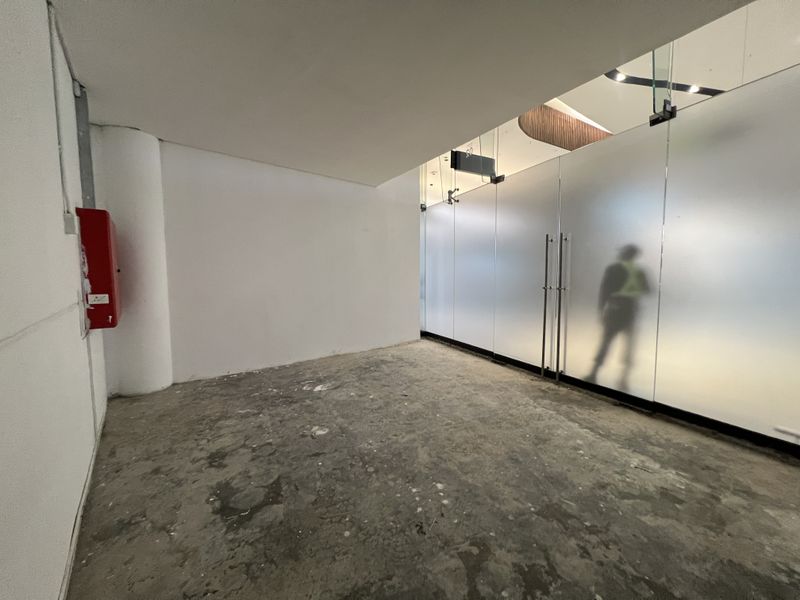 An empty commercial entry space featuring a frosted glass partition wall and unfinished concrete flooring, suitable for retail or office fit-out.