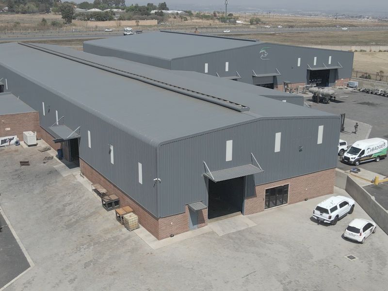 Aerial view of a large industrial warehouse complex featuring metal cladding, brick base, and extensive paved yard space with multiple access points.
