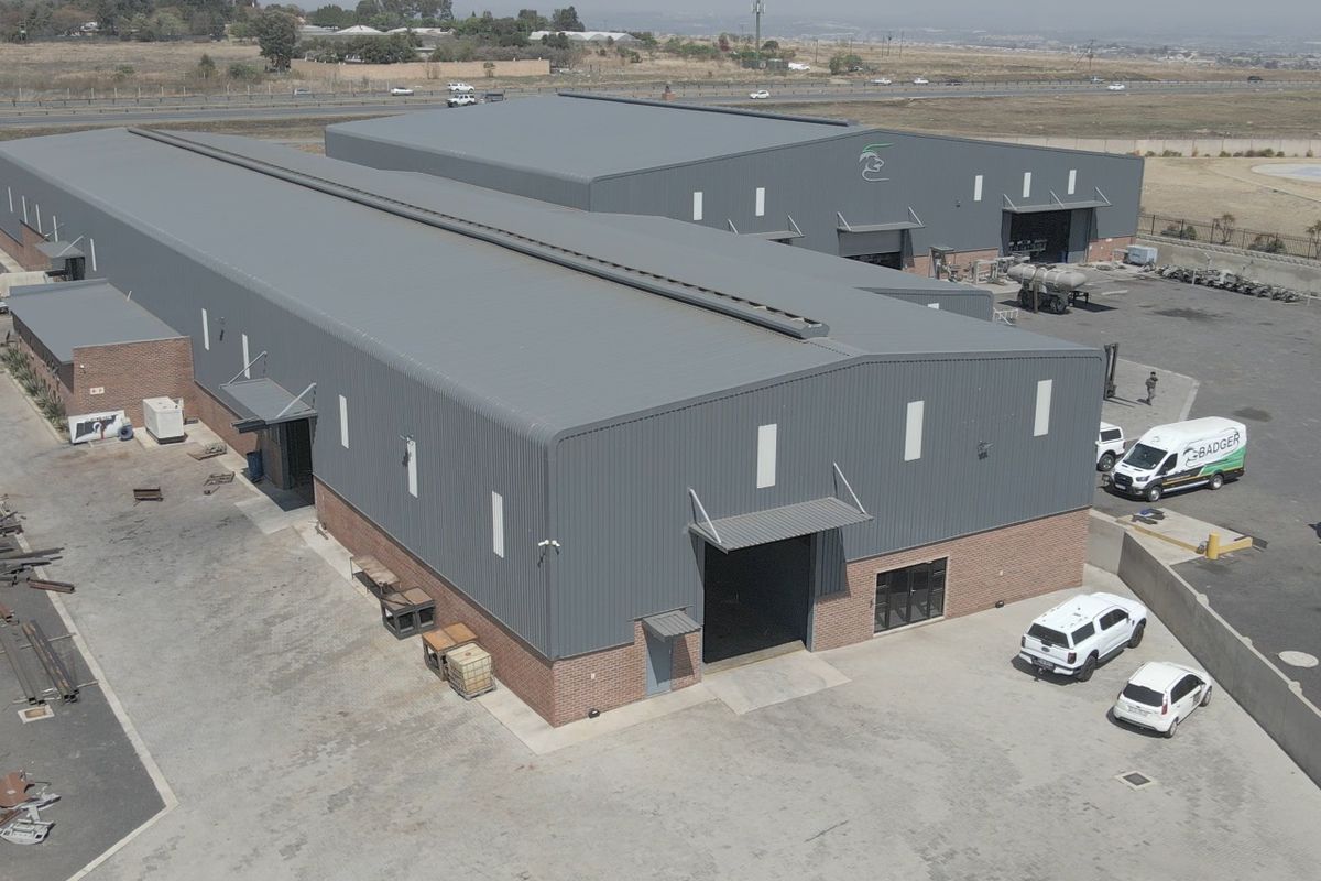 Aerial view of a large industrial warehouse complex featuring metal cladding, brick base, and extensive paved yard space with multiple access points.