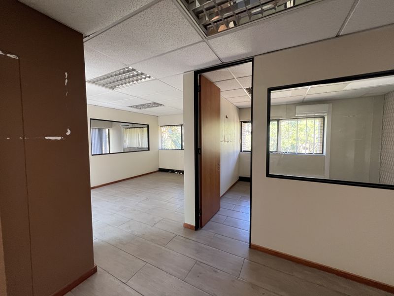 Empty office space featuring tiled flooring, suspended ceilings with recessed lighting, and internal glass partitions providing a bright, professional work environment.