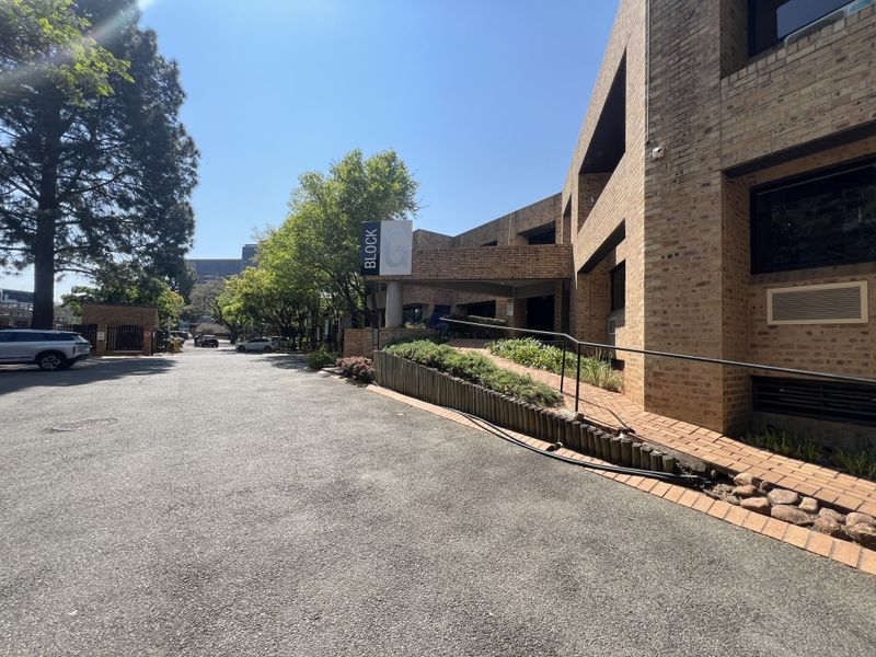 Exterior view of the office building entrance featuring a brick facade, paved driveway, and accessible ramp with handrail.