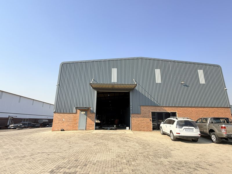 Front elevation of a modern industrial warehouse featuring a large roller door, brick and metal cladding, and a spacious paved yard area.