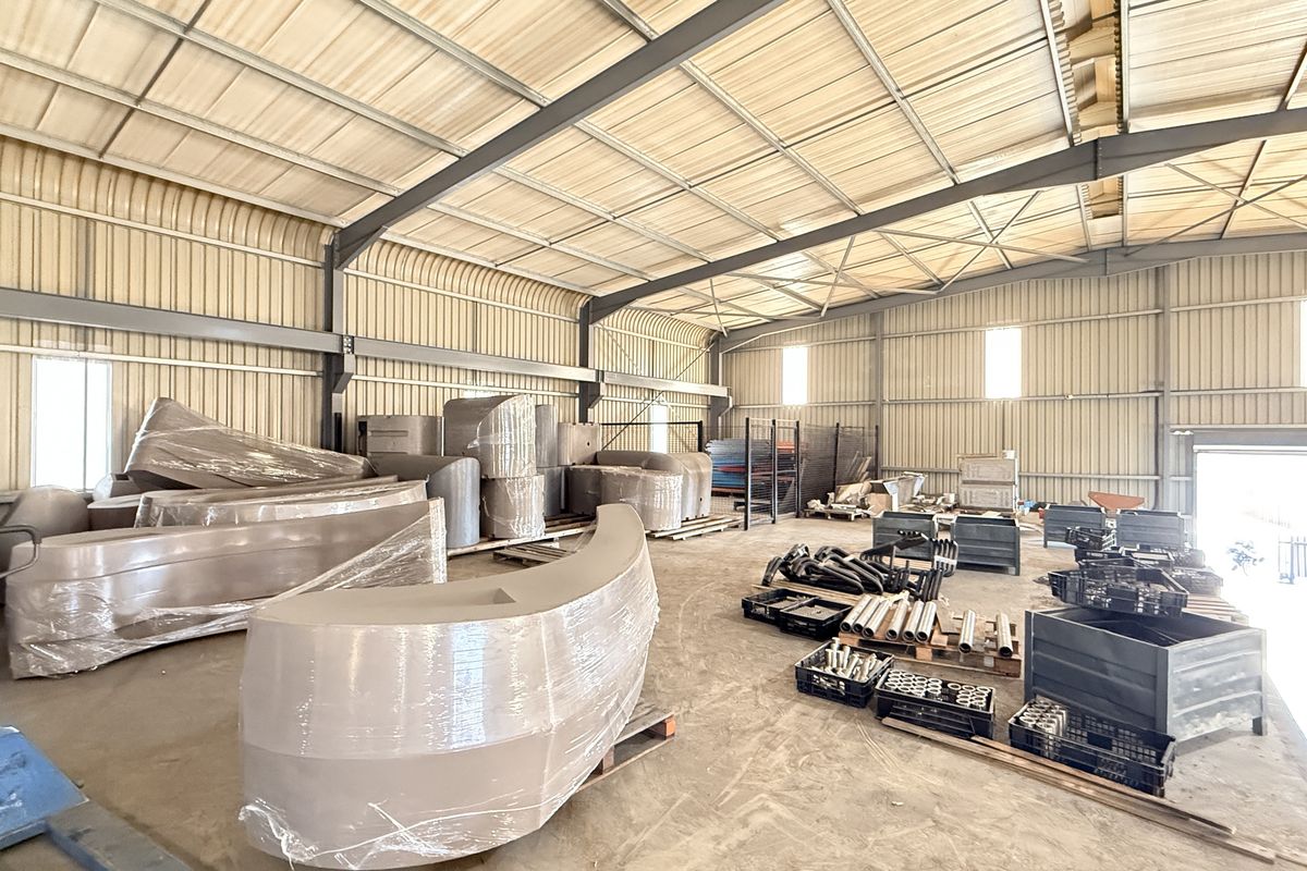 Spacious industrial warehouse featuring a steel portal frame, corrugated metal walls, concrete flooring, and a large roller shutter door for easy access.