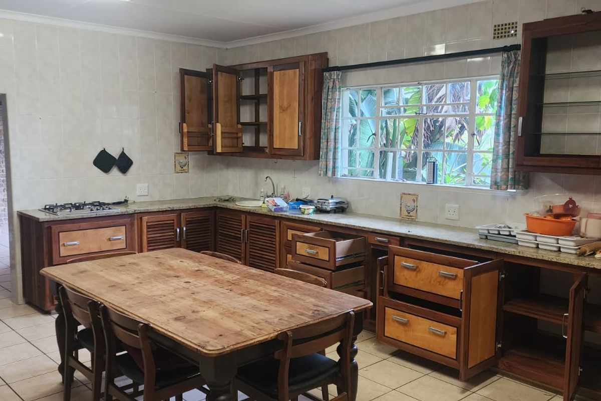 A dated kitchen featuring wooden cabinetry, granite countertops, and a gas hob, requiring cosmetic updates to modernize the space.