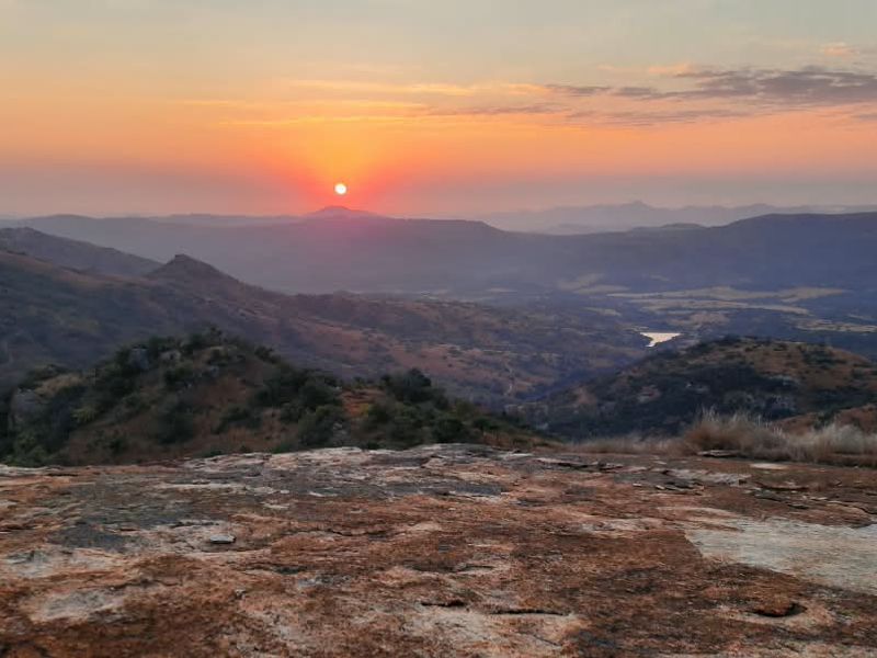 A scenic sunset view overlooking the expansive hilly landscape and natural terrain of the farm property.