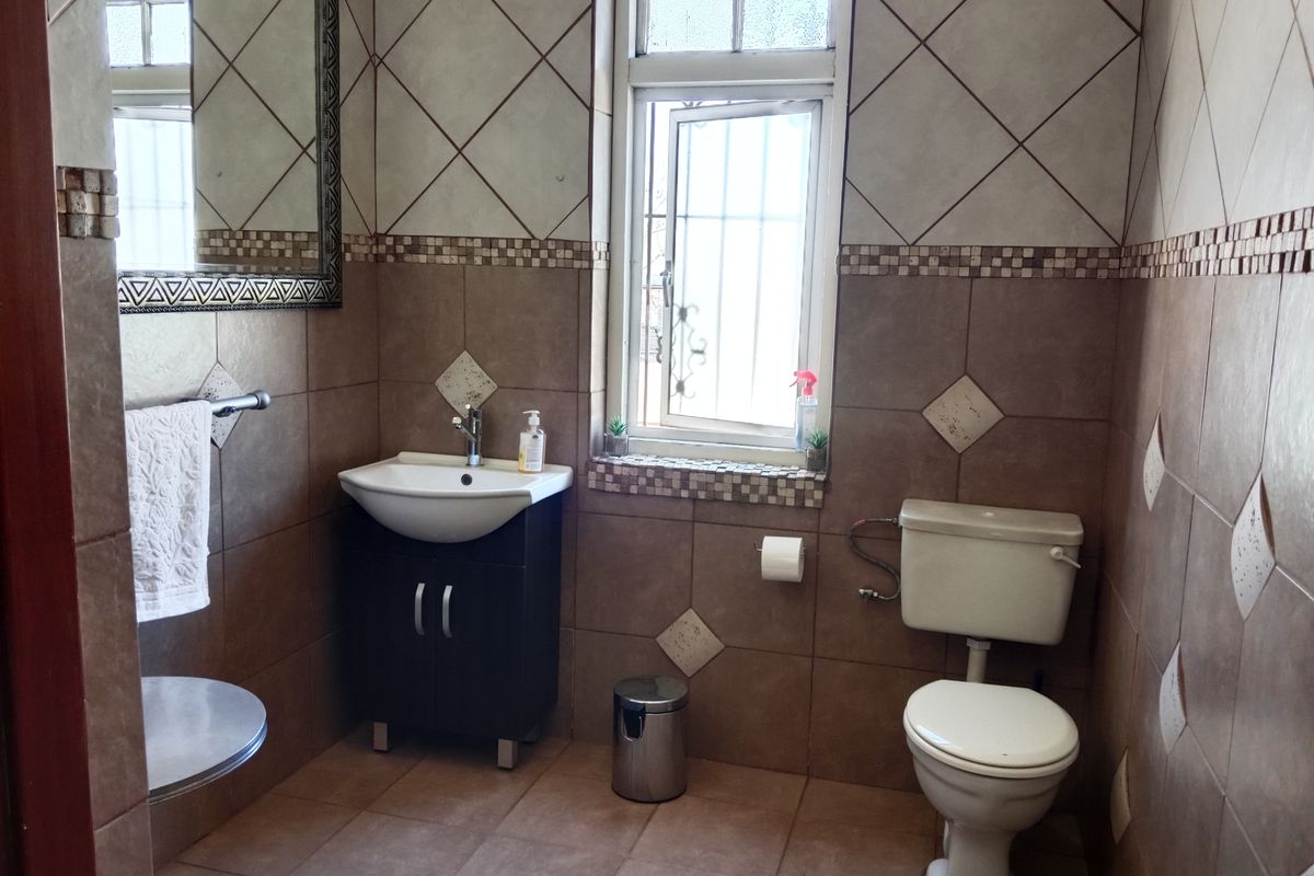 A functional bathroom featuring tiled walls and flooring, a vanity cabinet with a basin, and a standard toilet.