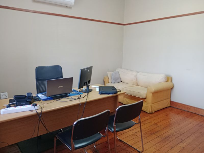 A functional office space featuring original timber flooring, picture rails, and a wall-mounted air conditioning unit.