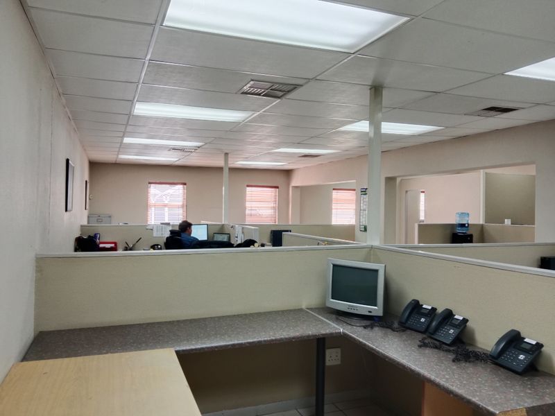 Open-plan office space featuring built-in partitions, laminate work surfaces, and a suspended ceiling with recessed lighting.