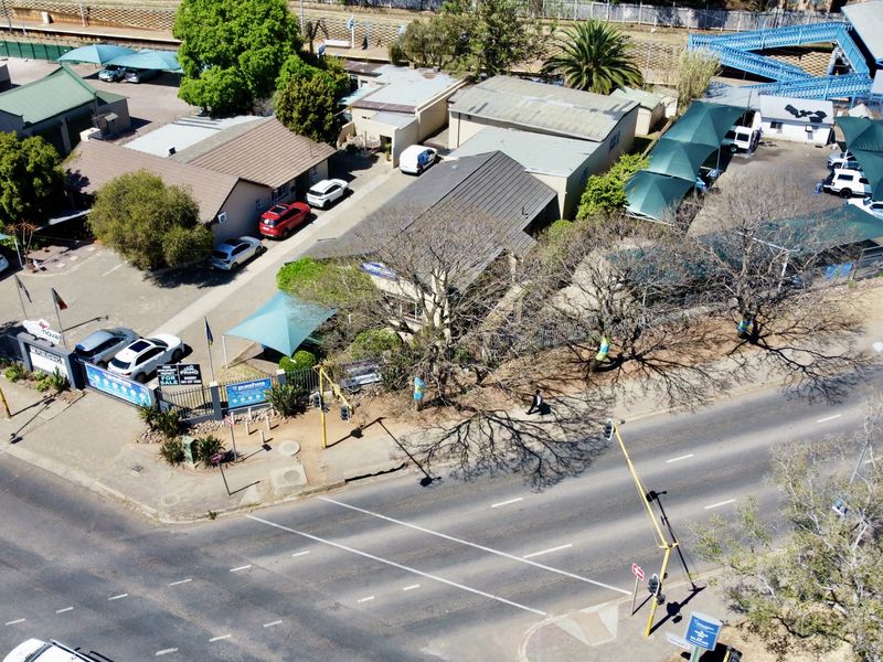 Aerial view of a commercial office property featuring multiple buildings, paved parking areas with shade cloth carports, and perimeter security fencing.