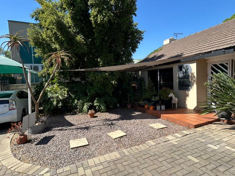Front exterior view of the office property featuring a paved driveway, gravel garden area, tiled entrance porch, and shade sail covering the entrance.