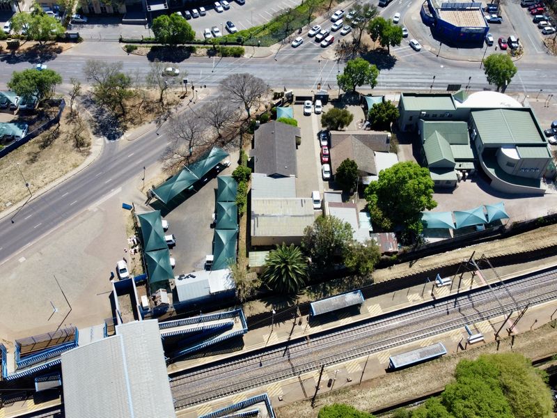 Aerial view of a commercial office property featuring extensive parking with shade structures, adjacent to a railway line and pedestrian infrastructure.