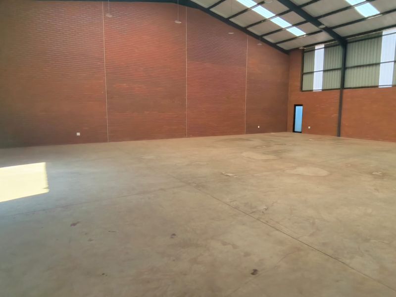 Spacious industrial warehouse unit featuring exposed brick walls, polished concrete flooring, high-clearance steel frame, and natural light through integrated skylights.