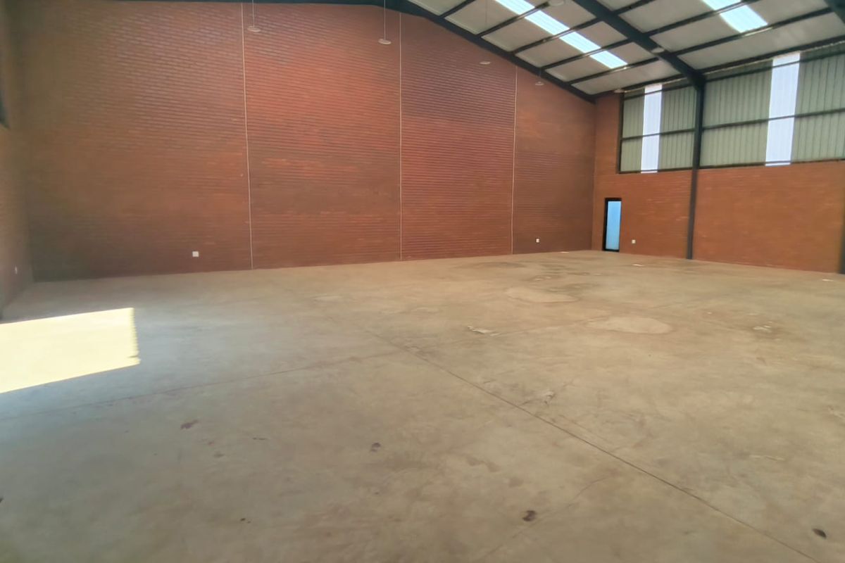 Spacious industrial warehouse unit featuring exposed brick walls, polished concrete flooring, high-clearance steel frame, and natural light through integrated skylights.