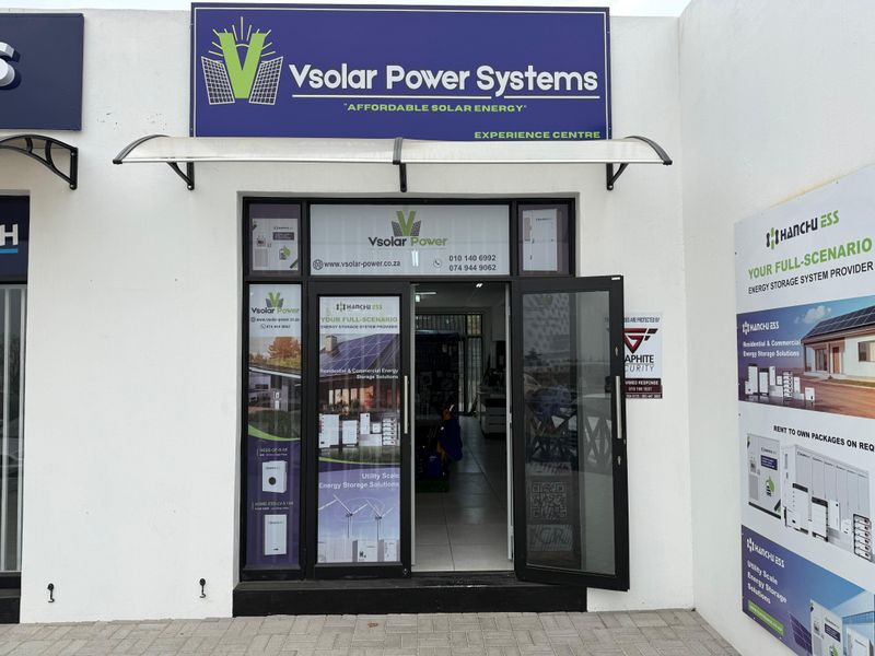 Front entrance of a commercial retail unit featuring glass doors, branded signage, and a protective awning.