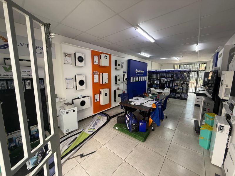 A commercial retail showroom space featuring tiled flooring, suspended ceilings, and wall-mounted product display units for solar energy systems.