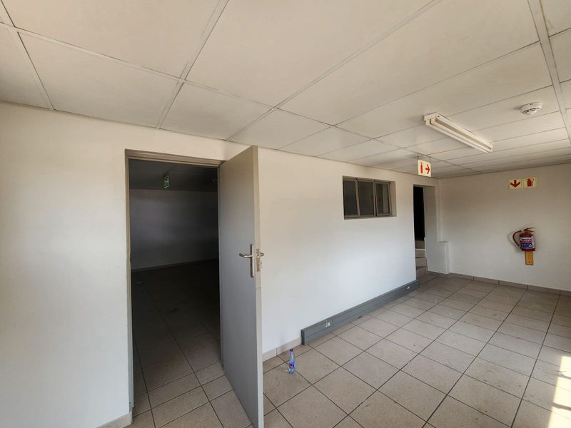 A functional industrial utility space featuring tiled flooring, suspended ceiling with fluorescent lighting, and essential fire safety equipment.