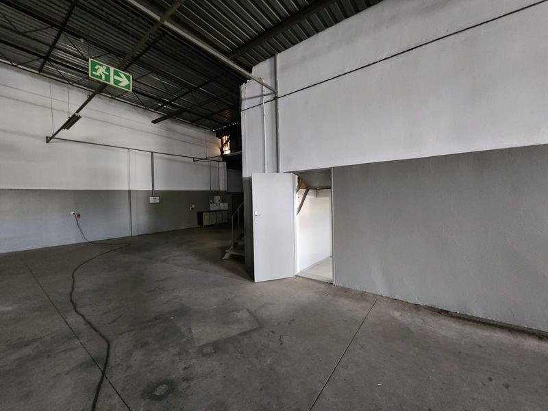 Spacious industrial utility area featuring high exposed ceilings, durable concrete flooring, and direct internal access, suitable for storage or workshop operations.