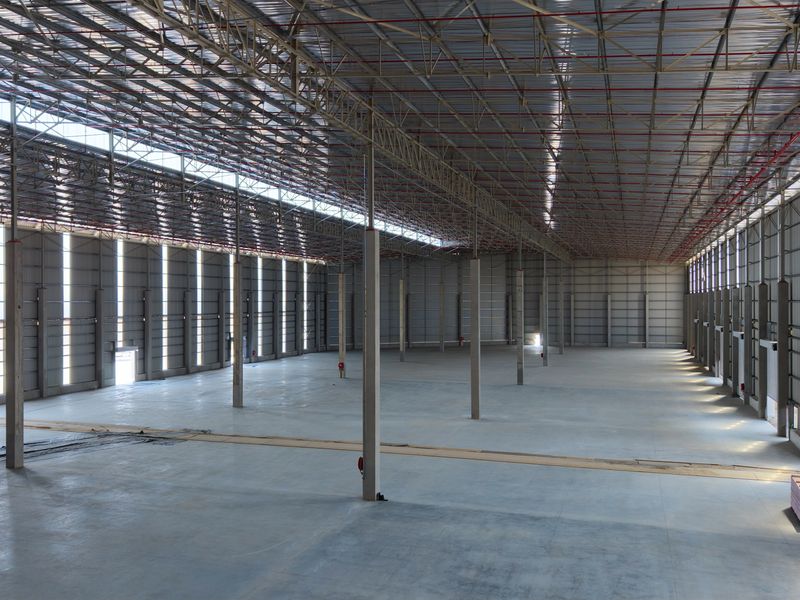 Expansive industrial warehouse space featuring high ceilings with exposed steel trusses, polished concrete flooring, and integrated fire sprinkler systems.