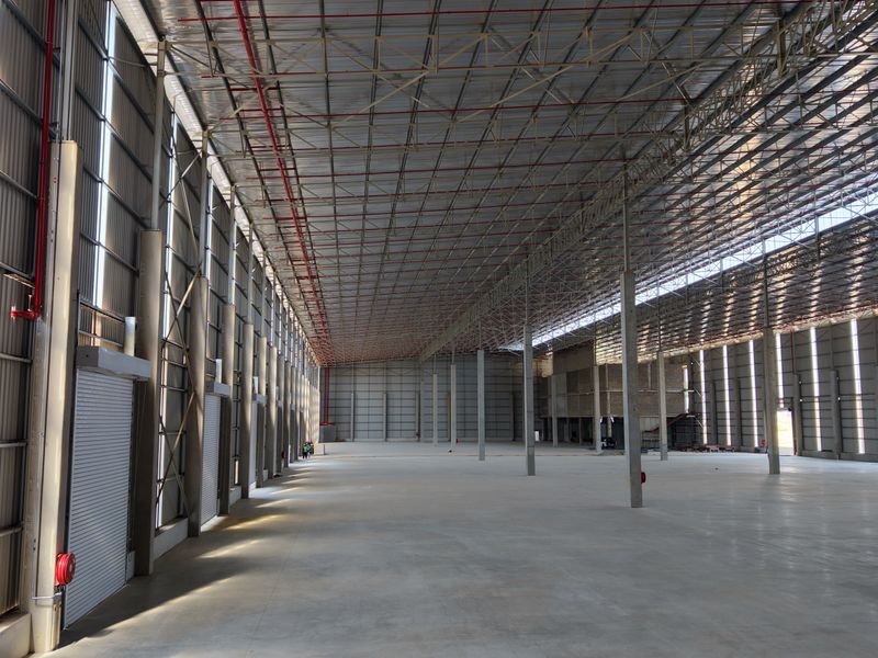Spacious industrial warehouse featuring high ceilings, concrete flooring, steel portal frame construction, and multiple roller shutter doors for efficient logistics and storage operations.