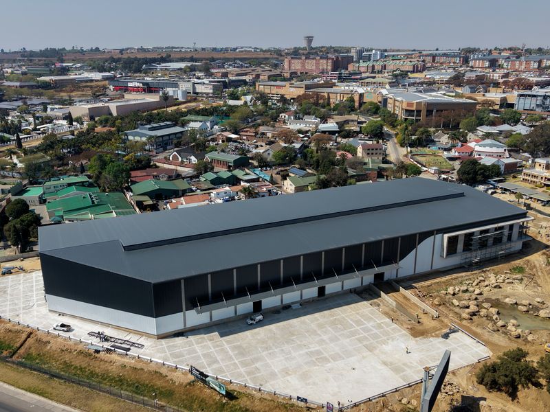 Aerial view of a large industrial warehouse facility featuring a expansive concrete yard and modern metal roofing, situated in a commercial area.