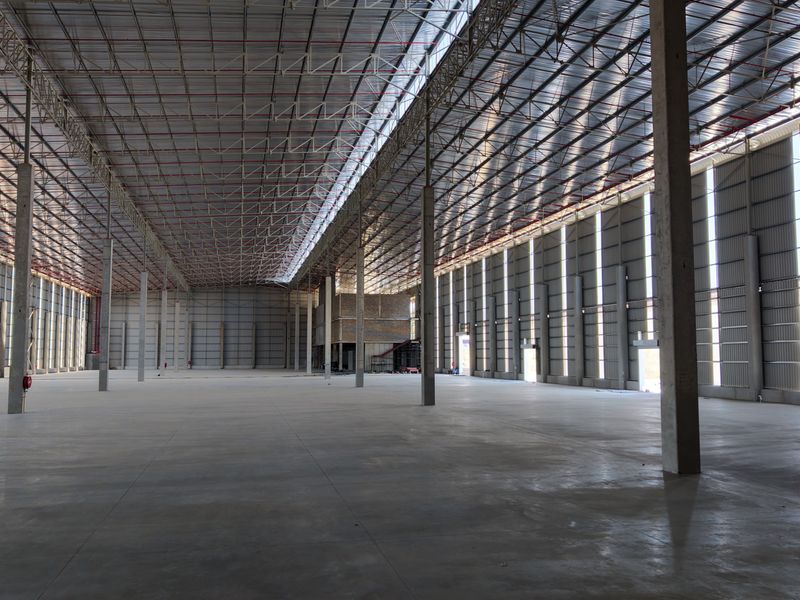 Spacious industrial warehouse featuring high ceilings, concrete flooring, steel truss roofing, and integrated fire sprinkler systems, suitable for large-scale storage or manufacturing operations.
