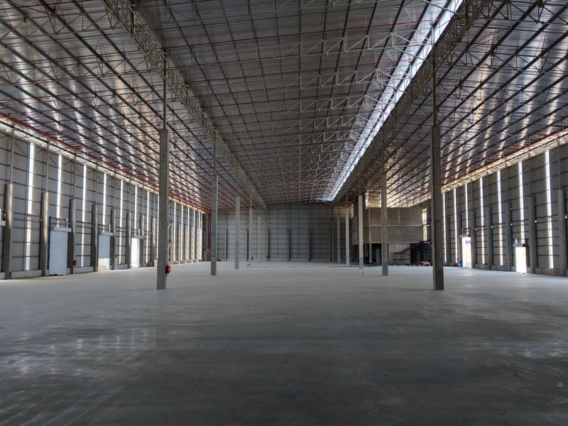 A large, open-plan industrial warehouse space featuring high ceilings, concrete flooring, and robust steel structural elements, suitable for logistics or manufacturing operations.