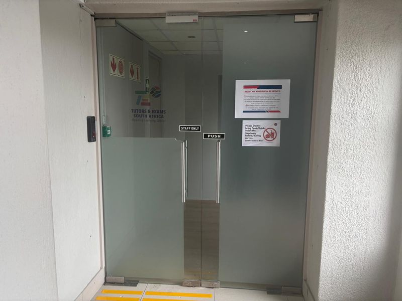 Main entrance featuring glass double doors with an integrated access control system and overhead door closer.