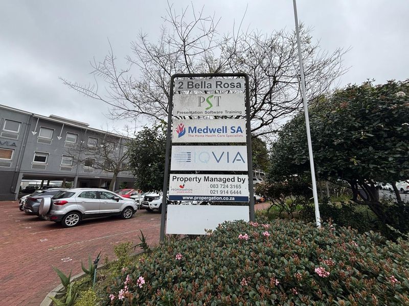 Exterior view of the office property entrance featuring a prominent tenant directory sign and paved parking area.