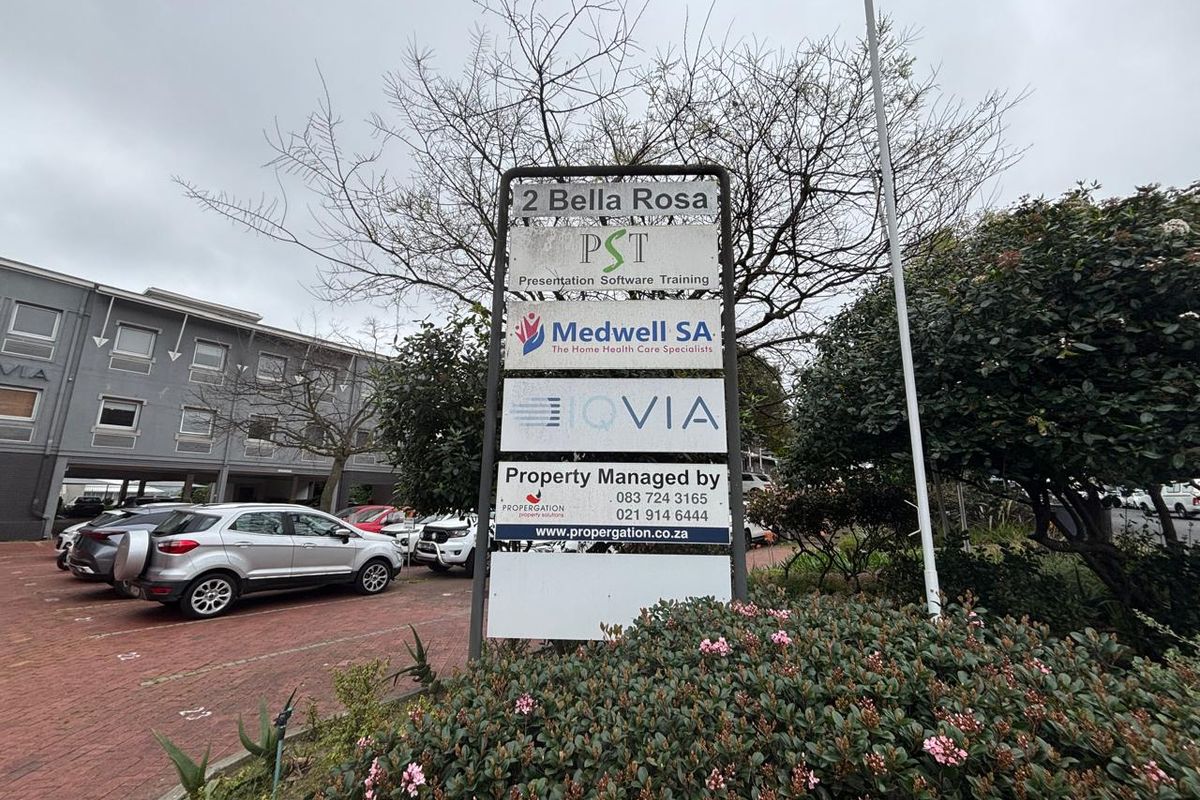 Exterior view of the office property entrance featuring a prominent tenant directory sign and paved parking area.