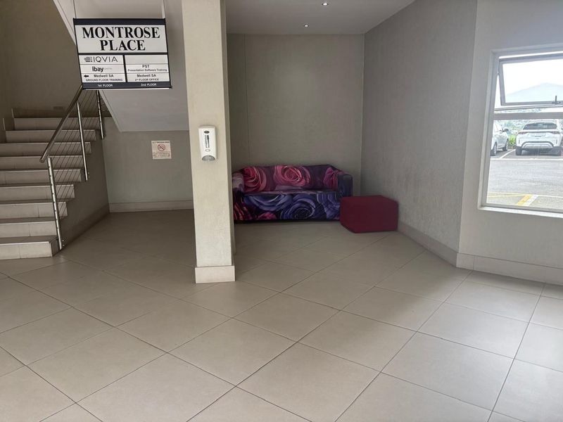 Office building entrance lobby featuring tiled flooring, a staircase with stainless steel handrails, and directional signage for tenants.
