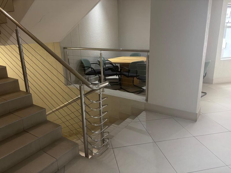 Office interior featuring a modern stainless steel staircase balustrade and tiled flooring, providing a functional and professional workspace layout.
